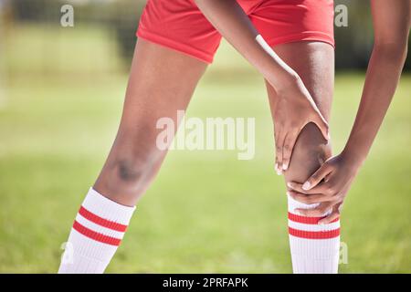 Fußball-Knieschmerzverletzung einer Spielerhand und eines Spielers auf einem Feld mit Nahaufnahme für Krankenkasse oder anatomischen Hintergrund. Unten von Fußball oder Sportler mit Knochenbruch Notfall oder Sportunfall Stockfoto