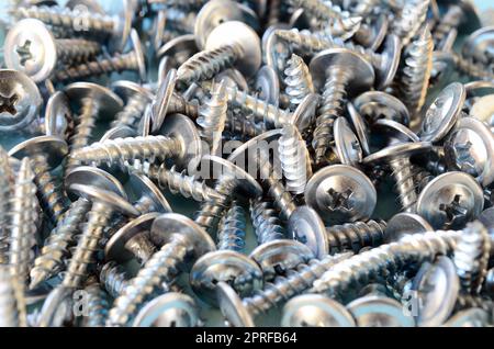 Viele kleine silberne Schrauben sind in einem großen chaotischen Haufen. Nahaufnahme Makro anzeigen Stockfoto