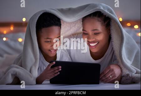 Eine Familie zu sein, bedeutet, dass du Teil von etwas bist. Eine Mutter und ein Sohn, die ein Tablet im Bett oder zu Hause benutzen Stockfoto