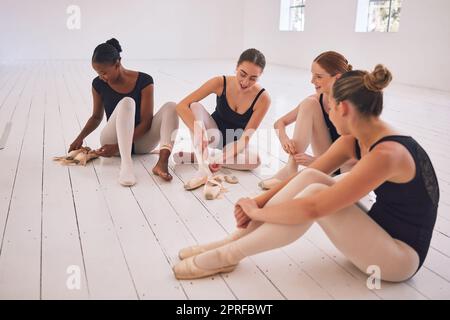 Fitness, Training und die Kunst des Balletttanzes, eine Gruppe von lächelnden jungen Tänzern, die nach dem Training auf dem Boden sitzen. Glückliche und müde Ballerina-Mädchen entspannen sich, reden und teilen Ideen im Tanzstudio Stockfoto