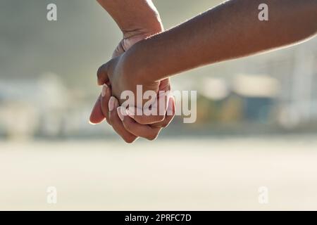 Hand in Hand. Nahaufnahme eines Erwachsenen, der eine Hand eines Kindes nach draußen hält. Stockfoto