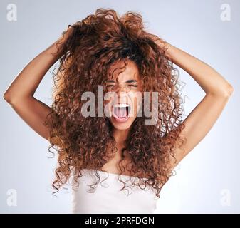 Es ist ein Albtraum. Eine attraktive junge Frau, die im Studio frustriert aussieht, vor grauem Hintergrund Stockfoto