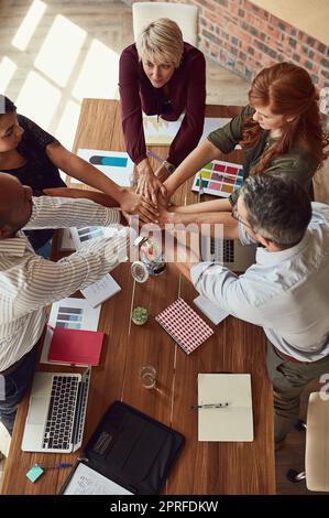 Lassen Sie uns diesem Projekt alles geben. Eine Gruppe von Kollegen, die sich bei einem Treffen in einem modernen Büro solidarisch in die Hände schlossen, wurde aus einem Blickwinkel aufgenommen. Stockfoto