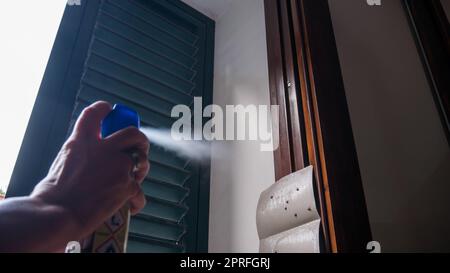 Hand mit Mückeninsektizid-Spray zum Töten von Fliegen und Mücken. Deutlich sichtbare Hintergrundbeleuchtung mit Tröpfchen. Stockfoto