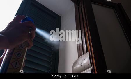 Hand mit Mückeninsektizid-Spray zum Töten von Fliegen und Mücken. Deutlich sichtbare Hintergrundbeleuchtung mit Tröpfchen. Stockfoto