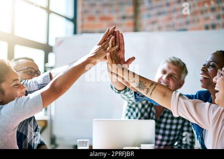 Sie haben eine Leidenschaft für alle künstlerischen Dinge. Ein Team von motivierten Kreativen geben einander eine hohe fünf. Stockfoto