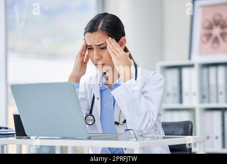 Stress oder Burn-out mit dem Arzt, der an einem Laptop denkt und daran arbeitet, in der Sprechstunde oder Praxis des Krankenhauses. Medizinisches Fachpersonal oder spezialisierter Chirurg mit Angst Kopfschmerzen durch psychische Probleme Stockfoto