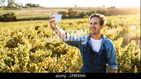 Ich möchte meine Fortschritte teilen. Ein junger Mann, der ein Selfie mit seinem Handy gemacht hat, während er auf einer Farm arbeitete. Stockfoto