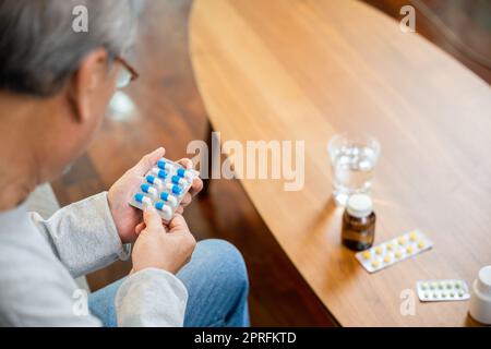 Asiatischer alter Mann kaufen pflanzliche Selbstkur Rx Pille online aus der Apotheke, besorgt Senior Mann mit Medikamenten Pillen, die er auf lesen, wie man Pillen vor der Einnahme zu nehmen Stockfoto