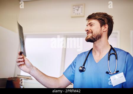 Ich glaube, ich habe herausgefunden, wo das Problem liegt: Ein junger Arzt, der allein in seinem Büro eine Röntgenaufnahme analysiert. Stockfoto