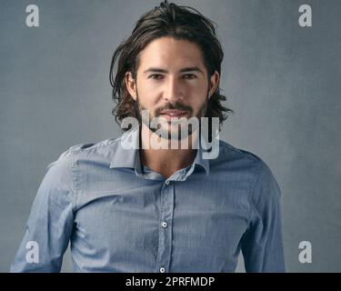 Hes eine gut aussehende Fella. Ein hübscher junger Mann, der vor einem grauen Hintergrund posiert. Stockfoto