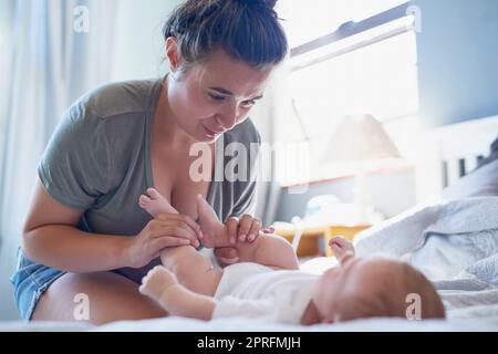 Eine junge Mutter, die ihre Beine hält und besorgt aussieht. Stockfoto