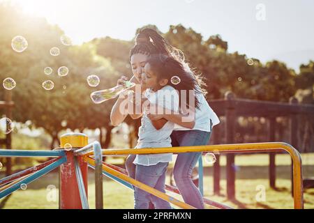 Blasen machen die Welt heller. Eine Mutter und ihre Tochter blasen Blasen im Park. Stockfoto