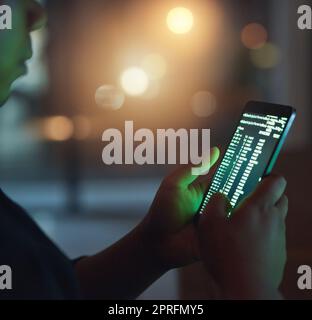 Hacker kennen ihr Handwerk sehr gut. Ein nicht erkennbarer Hacker, der im Dunkeln ein Handy benutzt. Stockfoto