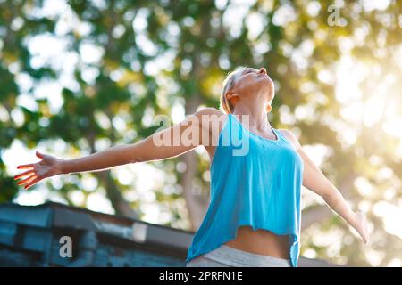 Ich bin endlich frei. Low-Angle-Aufnahme einer reifen Frau, die sich frei fühlt und mit ausgestreckten Armen im Freien posiert. Stockfoto