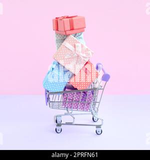 Viele bunte vorhanden Boxen in Supermarkt Einkaufswagen in violett unterlegt. Geschenke für Winterurlaub Stockfoto