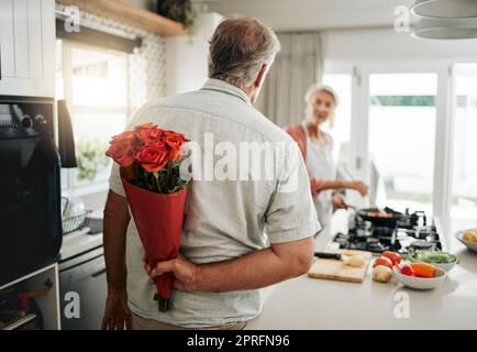 Überraschung, Rosen und ein Seniorenpaar zu Hause mit einem romantischen Mann verwöhnen Frau mit einem Blumenstrauß an einem Jahrestag, Geburtstag oder Valentinstag Stockfoto