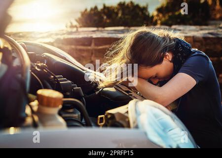 Sowohl sie als auch ihr Auto durchmachen einen Zusammenbruch. Eine junge Frau, die aufgeregt aussieht, nachdem sie am Straßenrand zusammengebrochen ist. Stockfoto