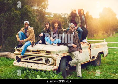 Kaltes Wetter, warme Herzen. Porträt einer Gruppe von Freunden, die auf einem Feld um einen alten Lastwagen posierten. Stockfoto