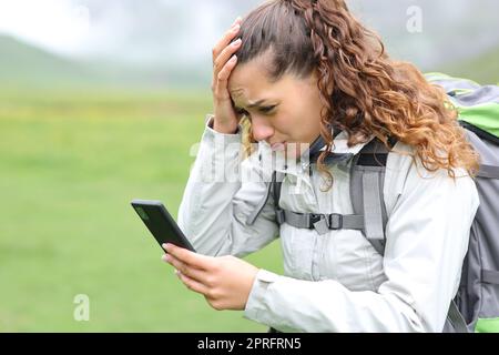 Besorgter Wanderer, der Nachrichten über Smartphones oder gps-Standorte in den Bergen nachlesen kann Stockfoto