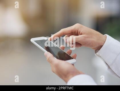 Scrollen durch seine Termine. Ein unkenntlich Geschäftsmann mit seinem Handy. Stockfoto