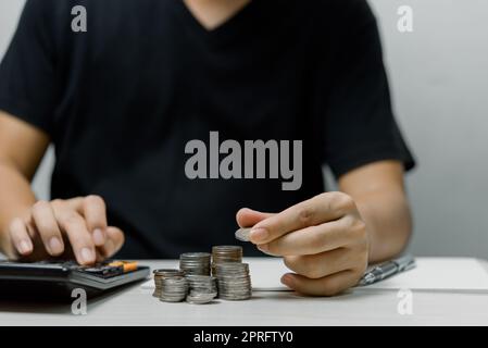 Geschäftsmann legte Münzstapel Geld und viele Banknoten im Büro.Business-Investitionen Buchhaltung finanzieren Sparen Sie Geld für die Zukunft und den Ruhestand. Stockfoto