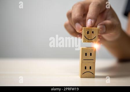 Kundenservice und Zufriedenheitskonzept Happy Smiley Face Icon.Business Feedback positive Bewertung sehr beeindruckt Holzwürfel auf dem Tisch. Stockfoto