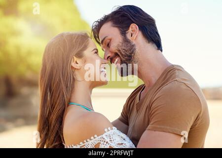 Liebe unter der Sommersonne. Ein lächelndes junges Paar umarmt, während es einen Tag zusammen im Park genießt. Stockfoto