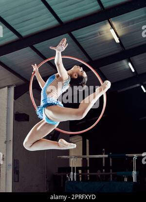 Sportlerin, Performance und Ring in der Luft für Turn-Show. Fitness-Girl mit künstlerischer Pose und Stretch für acrobat-Stunt. Junger und schöner Sportler im Fitnessstudio mit Hula-Reifen und flexiblem Körper. Stockfoto