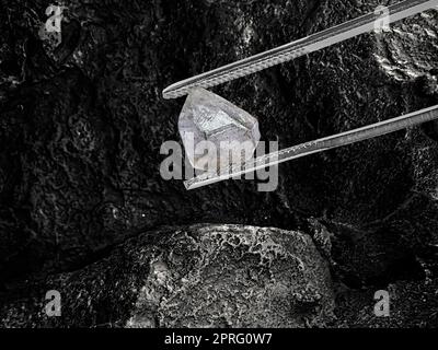 Natürlicher Diamant in Pinzette auf schwarzem Kohlehintergrund Stockfoto