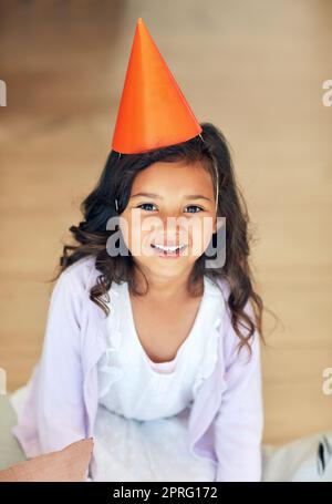 Ich bin bereit, wo die Party. Portrait eines niedlichen kleinen Mädchens, das zu Hause einen Partyhut trägt. Stockfoto