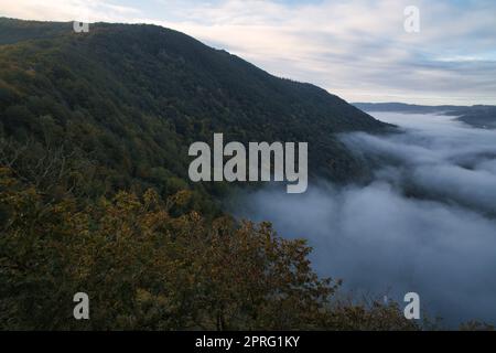 Nebel steigt auf den Bergen der kleinen Saarschleife. Mystische Stille an der Saar im Saarland. Stockfoto