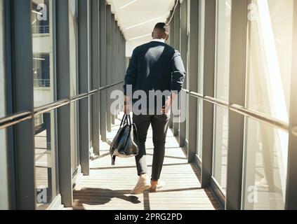 Geschäftsmann auf Geschäftsreise am Flughafen und männlicher afrikaner auf dem Weg in die Stadt. Transportservice vom Flugzeugterminal zum Hotel, Rückansicht eines modernen Mitarbeiters mit Handgepäck. Stockfoto