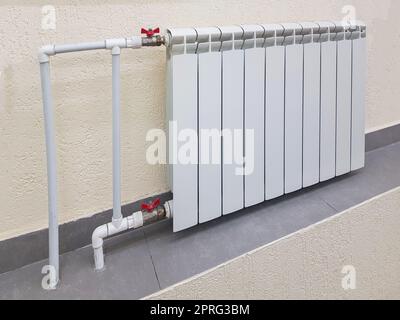 Weiße, moderne Aluminium-Heizkörperbatterie für Warmwasserheizung, auf dem Hintergrund einer Wand im Inneren eines Apartment- oder Bürobereichs Stockfoto
