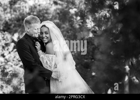 Portrait von interracial Jungvermählten Umarmung vor dem Hintergrund einer schönen Waldlandschaft, Schwarz-Weiß-Fotografie Stockfoto