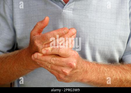 Linksseitige Finger eines Mannes, der seine rechte Hand und seinen Knöchel massiert Stockfoto