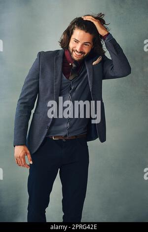 Sie sagen, dass Kleidung den Mann macht, ich sage, es sind die Haare. Studioaufnahme eines stilvoll gekleideten, hübschen jungen Mannes, der mit der Hand im Haar steht. Stockfoto