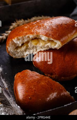 Nahaufnahme von hausgemachten Brötchen mit Scheiben von Äpfeln im Inneren auf dunklem Hintergrund. Stockfoto