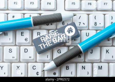 Textzeichen mit der Anzeige „Messlatte anheben“. Das Geschäftskonzept setzt höhere Maßstäbe und setzt auf der Suche nach Exzellenz den Stift in der Hand, der für erfolgreiche Teamarbeit steht. Stockfoto