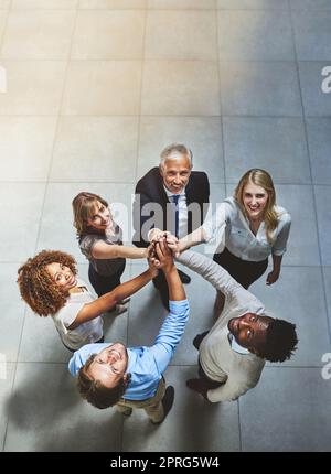 Hervorragende Zusammenarbeit. Eine Gruppe von Kollegen, die sich gegenseitig in Solidarität eine hohe Fünftel gaben, wurde in einem hochgedrehten Bild aufgenommen. Stockfoto