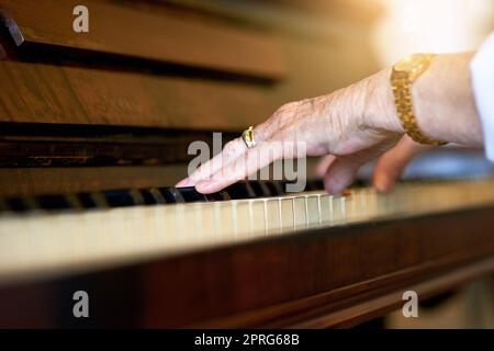 Sie erinnert sich noch immer an die Melodie. Eine nicht identifizierbare ältere Frau spielt zu Hause Klavier. Stockfoto