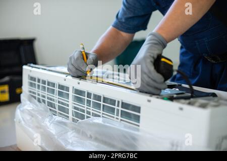 Männlicher Techniker markiert die Messung der Klimaanlage mit einem Bleistift. Stockfoto