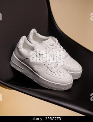 Nahaufnahme von lässigen, bequemen weißen Sneakers auf schwarzem und beigefarbenem Hintergrund. Stockfoto