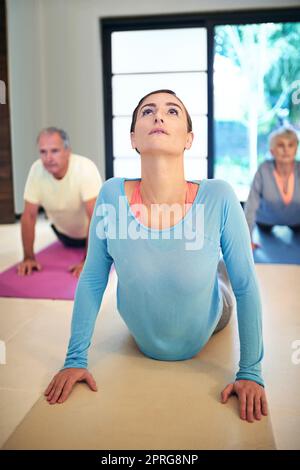 Je gesünder du bist, desto besser fühlst du dich. Ein Yogalehrer leitet ein Seniorenpaar in einem Yogakurs. Stockfoto