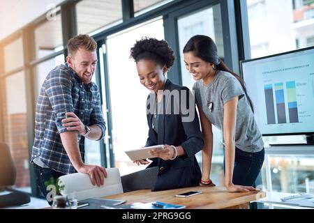 Teamwork kommt allen im Unternehmen zugute. Ein Team junger Kollegen nutzt bei der Arbeit gemeinsam ein digitales Tablet. Stockfoto