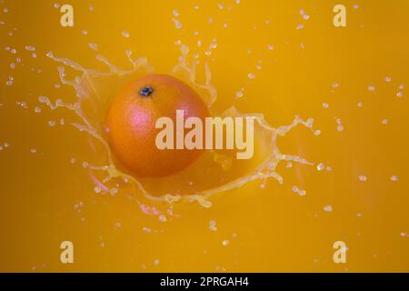 Ein Getränk mit Orangensaft, der mit Fruchtspritzern und Spritzgeschmack spritzt, mit einer flüssigen Explosion Stockfoto