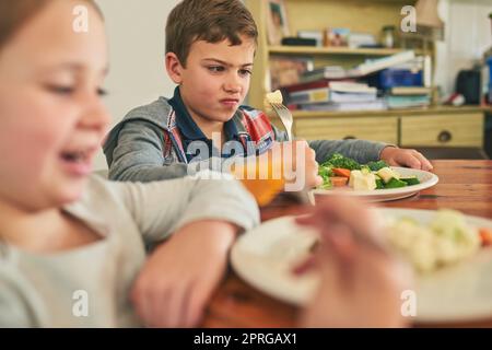 Was ist das überhaupt? Zwei mürrische Kinder weigern sich, ihr Gemüse zu essen. Stockfoto