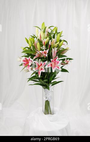 Schönes großes Bouquet von rosa Lilien in transparenter Glasvase. Stockfoto