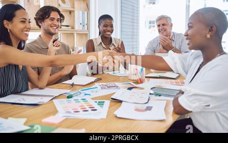 Kreative Geschäftsleute schütteln sich bei einem Meeting für Dankeschön, Förderung oder Design-Innovation und Erfolg mit Teamapplaus. Diversity-Gruppe, die sich die Hand schüttelt, um einen Deal, Teamwork oder eine Begrüßung zu vereinbaren Stockfoto