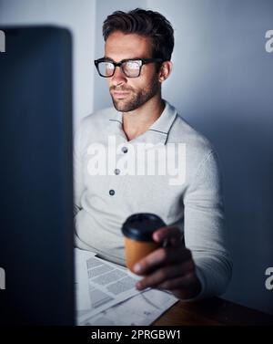 Ein hübscher junger Mann, der spät am Computer arbeitet. Stockfoto